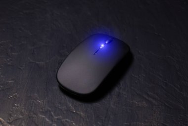 Siyah arkaplanda dizüstü bilgisayar için siyah kablosuz minimalist fare. Modern teknoloji aygıtı.