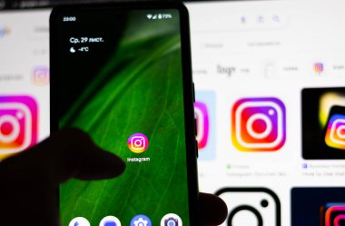 Kapat, Adam elinde sosyal internet servisi Instagram 'ı olan bir akıllı telefon tutuyor..