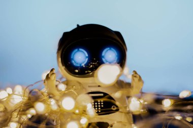 Yeni yılda Yapay Zeka Yayılması ve Geliştirilmesi. Mavi arka planda çelenkleri olan küçük gerçek bir robot. Modern dijital teknoloji kavramı.