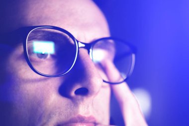 Tired man in glasses works on internet. Migraine or headache after work in front of computer all day. Eye pain, dry eye syndrome.