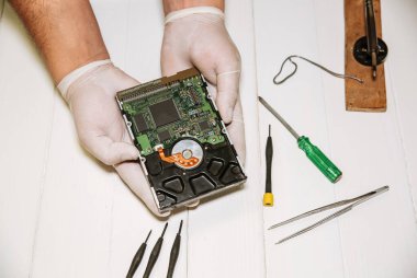 Adam sabit diski tamir ediyor. Eski kişisel bilgisayarın içinde. Kırık bilgisayar. Tornavida ve kıskaçlar ellerinde..