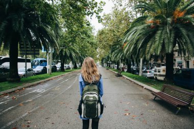 BARCELONA, İspanya - 15 Ekim 2018 Barcelona 'daki modern İspanyol sokakları. Sırt çantalı hippi kız palmiye ağaçlarıyla arka sokakta duruyor. Güney şehrinde gezgin.