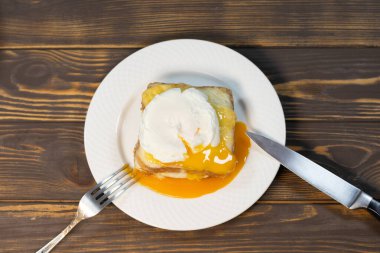 Dilimlenmiş jambonlu ızgara sandviç, erimiş peynir, dijon hardalı ve beşamel soslu haşlanmış yumurta..