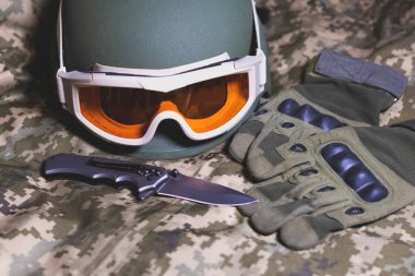 Taktik askeri eldivenler, miğfer, gözlük ve bıçak kamuflaj üniformasında. Asker mühimmatı.