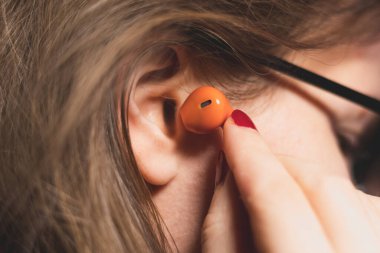 Kadın kulaklığa Orange Wireless Bluetooth kulaklığı yerleştiriyor. Modern Stereo Kulaklıklar, Spor Kulaklık.