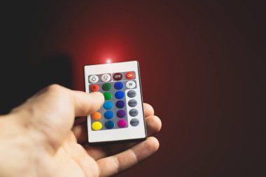 Adam Atmosfer Neon ışığını uzaktan kumandayla ayarlıyor ve kırmızı rengi açıyor. Renkli RGB ampulü. LED Çokrenkli Lump. Ev Işıklandırması. Bloglama ve iş dünyası modern havalı ışıklandırma.