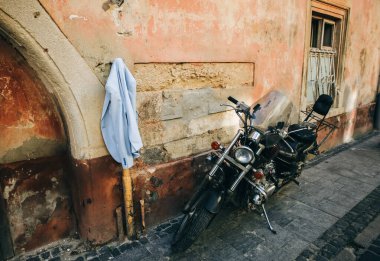 LVIV, UKRAINE - 18 Ağustos 2018: Takım elbise ceketi eski şehrin sokaklarında asılı. Modern siyah motosiklet yakında duruyor..