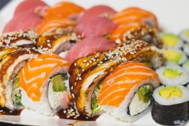 Lezzetli rengarenk farklı türde suşi ve yemek çubukları. Japon usulü akşam yemeği. Sağlıklı yiyecekler. Filadelfia ve Maki suşisi. Avokado, Tuna, Somon, balık ve karidesli..