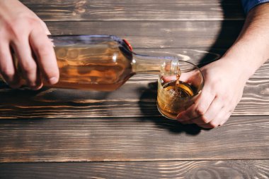 Alkolik bağımlısı. Şişeden cama dökülen bir adam. Tehlikeli bir alışkanlık. Sağlıksız yaşam konsepti. Sosyal sorun.