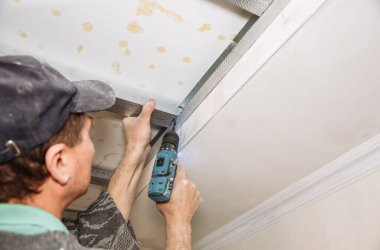 Adam matkapla çalışıyor ve tavanı geriyor. Bakım onarımı dairede tadilat yapıyor. İçerideki restorasyon.