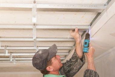 Adam matkapla çalışıyor ve tavanı geriyor. Bakım onarımı dairede tadilat yapıyor. İçerideki restorasyon.