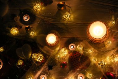 Güzel Noel ışıkları ve çelenk süslemeleri arasında yanan mumlar. Yılbaşı festivali geçmişi. Hediyeler, hediyeler, kış tatili için kartpostallar..