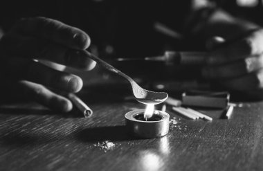 Eroini ateşe veren adam. İğne şırıngası. Uyuşturucu bağımlısı. Mumlar kibrit ve sigarayla yanıyor. Tehlikeli bir alışkanlık. Sağlıksız yaşam konsepti.