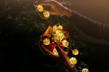 Kız yılbaşı ağacını ışıklarla süslüyor. İçinde kadın oyuncakları olan hediye kutusu. Aşk ve tatil kavramı. Yeni yıl havası. Hygge tarzı. Sihir zamanı.