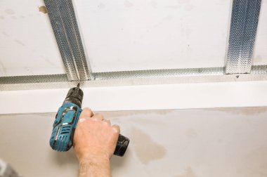 Adam matkapla çalışıyor ve tavanı geriyor. Bakım onarımı dairede tadilat yapıyor. İçerideki restorasyon.