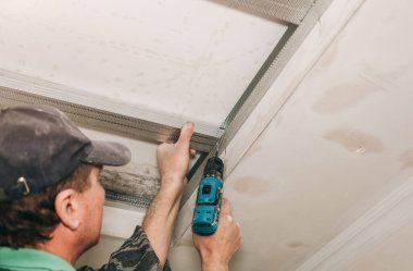 Adam matkapla çalışıyor ve tavanı geriyor. Bakım onarımı dairede tadilat yapıyor. İçerideki restorasyon.