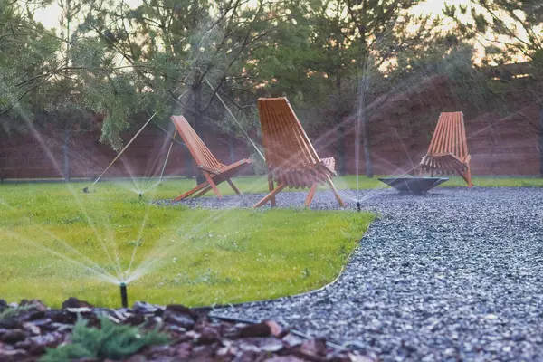 stock image Automatic lawn watering system. Sprinkler, Water spashes on green grass.