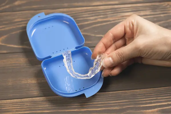 stock image Woman takes Dental splint mouth guard from the box. TMJ splint disorder treatment. Occlusal splint. Prevent bruxism. Mouth guard for TMJ. Teeth protection. Pain in jaw. Teeth grinding.