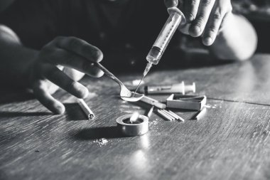Eroini ateşe veren adam. İğne şırıngası. Uyuşturucu bağımlısı. Mumlar kibrit ve sigarayla yanıyor. Tehlikeli bir alışkanlık. Sağlıksız yaşam konsepti.