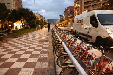 BARCELONA, SPAIN - OCTOBER 15, 2018: Modern Spanish streets in Barcelona. City life at night with bicycles parking. clipart