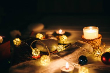 Güzel Noel ışıkları ve çelenk süslemeleri arasında yanan mumlar. Yılbaşı festivali geçmişi. Hediyeler, hediyeler, kış tatili için kartpostallar..
