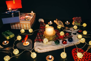 Güzel Noel ışıkları ve çelenkler arasında yanan mumlar. Yılbaşı festivali geçmişi. Hediyeler, hediyeler, kış tatili için kartpostallar..