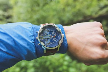 Mavi ceketli adamın elinde erkek saati var. Doğanın zarif aksesuarları..