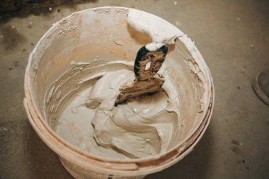 Adam kovada macun macununu karıştırıyor. Duvar gıcırtısı. Bakım onarımı dairede tadilat yapıyor. Kapalı alanda restorasyon. Somut arkaplan.