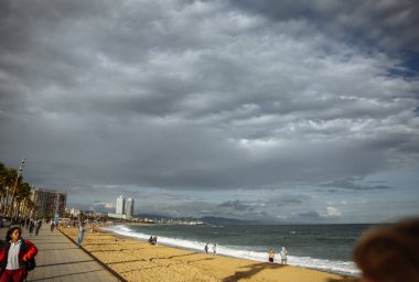 BARCELONA, İspanya - 15 Ekim 2018: insanlar Barcelona plajı boyunca yürüyorlar. İspanyol güneşli günü. Palmiye ağaçları.