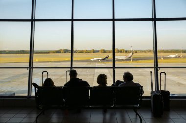 KATOWICE HAVAALANI, POLAND - 15 Ekim 2018: Havaalanında bavullarıyla oturan turistler. İnsanlar uçuşu bekliyor. Seyahat konsepti fotoğrafı. Gecikmiş uçak.