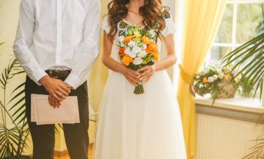 Nakış işlemeli elbiseli gelin ve damat kayıt belgelerini tutuyor. Ellerindeki buket çok güzel. Düğün günü merasimi. Geleneksel Ukrayna tarzı konsept.