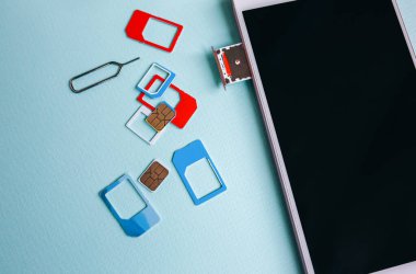 Masada duran modern akıllı telefon. Yakınlarda farklı mikro ve nano simülasyon kartları var. İletişim teknolojilerinde farklı nesiller.