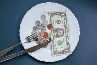 Çatal ve bıçakla tabakta bir dolar var. Para fotoğrafı yok. Fakirlerin fikri. Bozuk paralar. Küçük maaş ve emekli maaşı yiyecek için yeterli değil. Sosyal sorunlar.