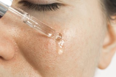 Yaklaş, kadın yüzüne nemlendirici serum yağı sürüyor. Güzellik tedavi prosedürü.
