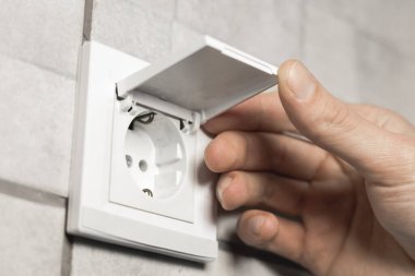 Adam banyoda kapağı olan su geçirmez elektrik prizi açıyor. Kapat..