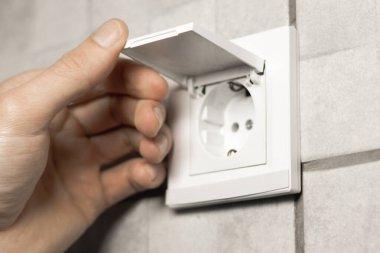 Adam banyoda kapağı olan su geçirmez elektrik prizi açıyor. Kapat..