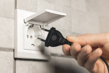 Adam prizin prizine su geçirmez elektrik prizi takıyor ve banyoda da kapağı var. Kapat..
