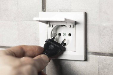 Adam prizin prizine su geçirmez elektrik prizi takıyor ve banyoda da kapağı var. Kapat..