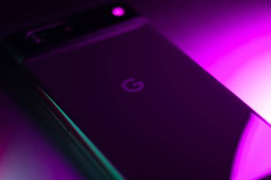 KYIV, UKRAINE - 20 Mart 2025: Modern akıllı telefon Google Piksel in neon mor ve yeşil ışıklar.