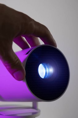 Mercekleri ayarlayan bir adamın dikey fotoğrafı modern kablosuz video projektörü ve mavi ışık. Video ya da fotoğraf sunumu ve amatör film izleme.