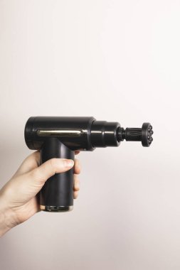 Eklemleri için küçük yuvarlak başlıklı perküsyon masaj tabancası tutan kadının dikey fotoğrafı. Fizyoterapi, kas düzeltme, kendine masaj aleti. Sağlık hizmetleri. Kapat..