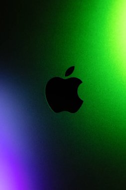 KYIV, UKRAINE - 15 Nisan 2025: Dikey fotoğraf, Apple şirketi logosu neon mor ve yeşil ışıklar. Modern teknoloji fotoğrafı.