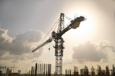 Large construction site including several cranes working on a silhouette complex, with cloudy background clipart