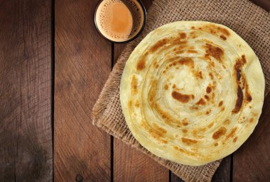 Indian, Pakistani Desi food paratha and chai. wooden background. clipart