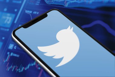 Karachi Pakistan - 12 Haziran 2023: Akıllı telefon ekranında Twitter logosu ve bulanık arkaplanda borsa grafiği.