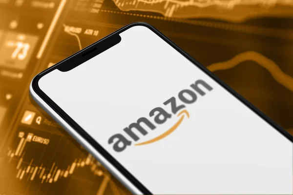 Karachi Pakistan - 12 Haziran 2023: Akıllı telefon ekranında Amazon logosu ve bulanık arka plandaki borsa grafiği.