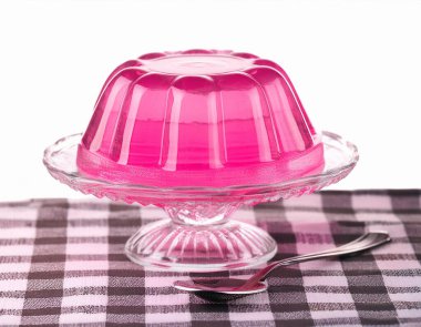 Kareli izole bir yerde cam bir kasede pembe jöle küpleri. ai oluşturuldu