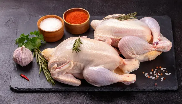 stock image Raw chicken with spices on a stone cutting board