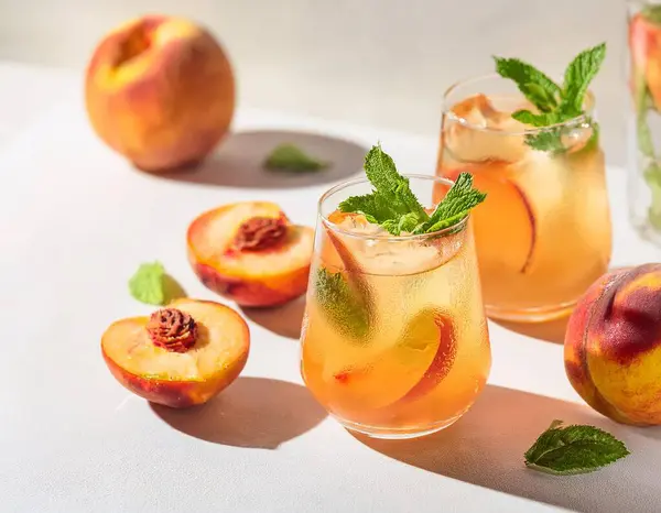 Soğuk şeftalili kokteyl ya da naneli buzlu çay. Beyaz arka planda şeftalili limonata. ai oluşturuldu