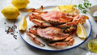 Akdeniz buğulamalı, pişmiş mavi yengeç, limon, zeytinyağı ve limon suyu soslu siyah bir tabak. İtalyan denizine yakalanmış. Karanlık taş arka plan. ai oluşturuldu